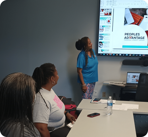 People sitting around a conference table watching a woman lead a presentation