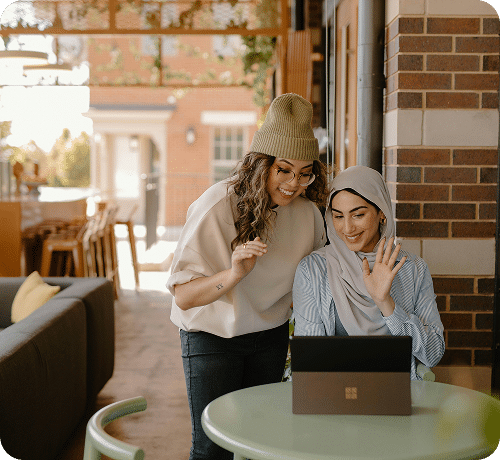 Two women looking at a laptop at a cafe