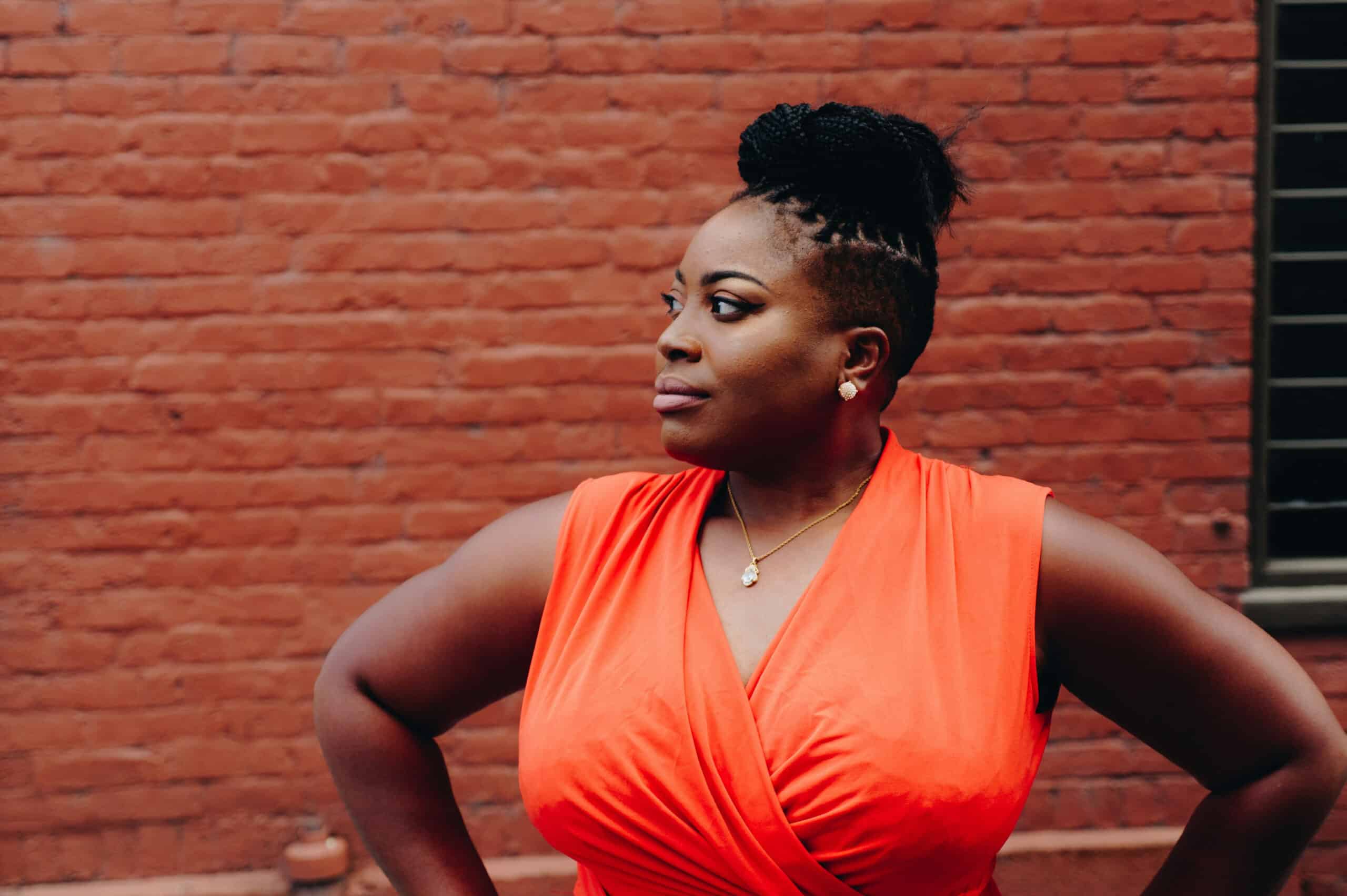Woman in red dress in front of a red brick wall