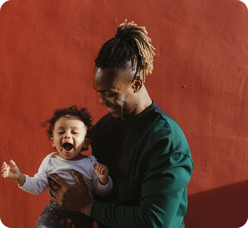 Man holding excited child in front of red wall